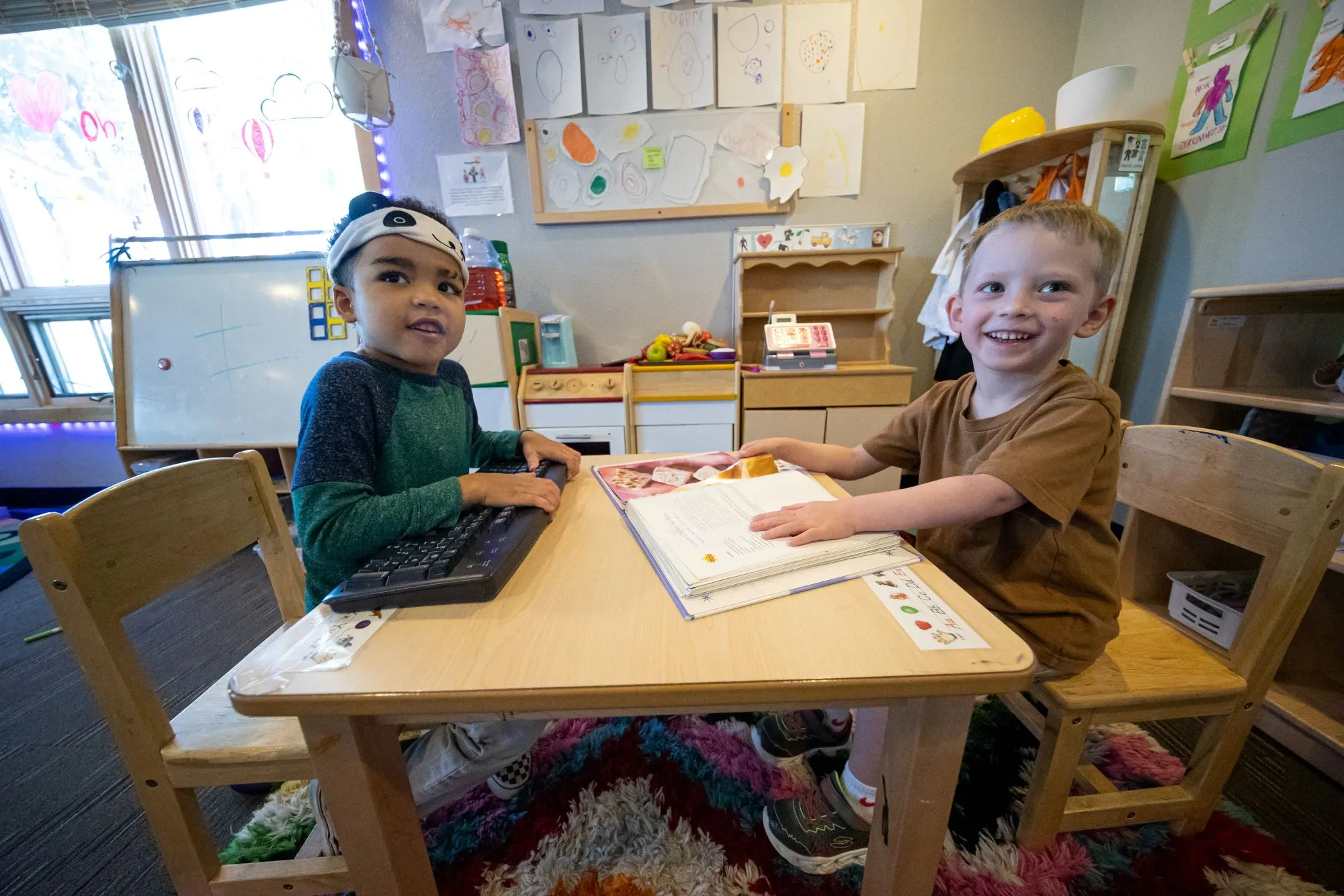 Two children playing with a keyboard and a book